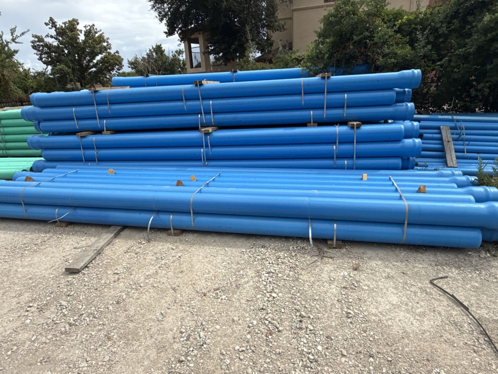 Stacks of blue PVC water pipe in an outdoor yard