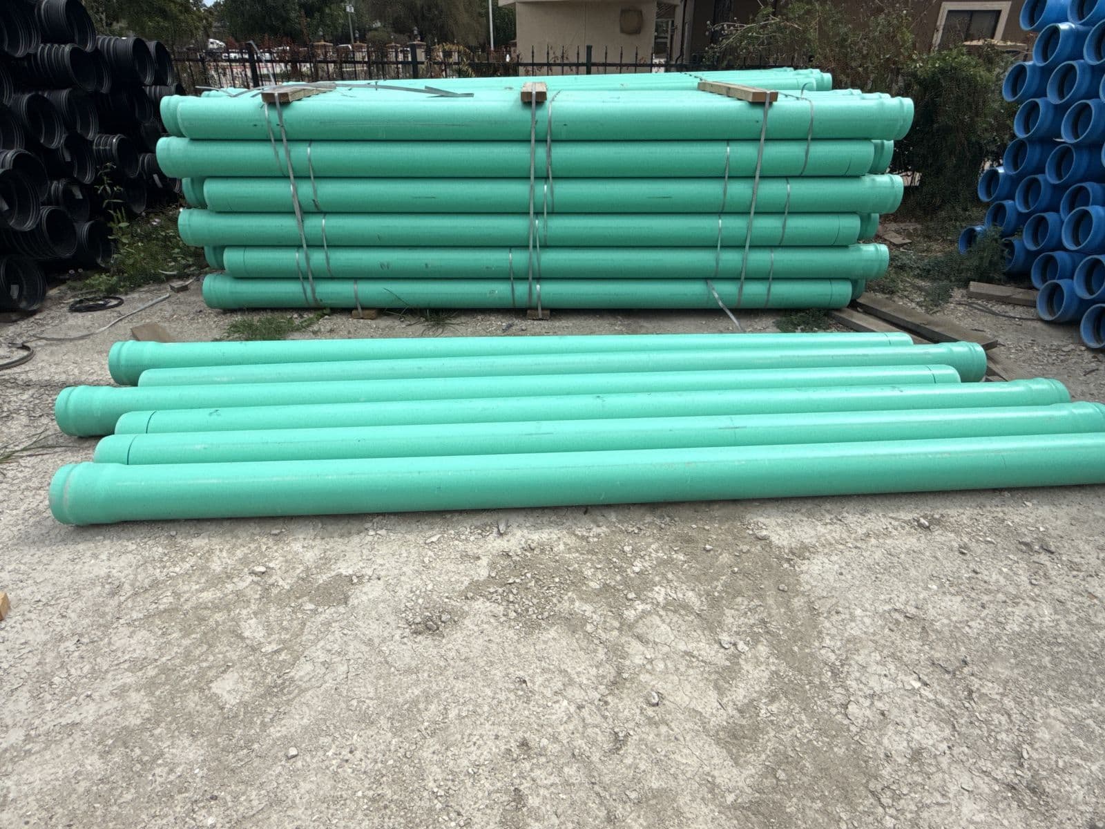 Stacks of green PVC sewer pipe in an outdoor yard