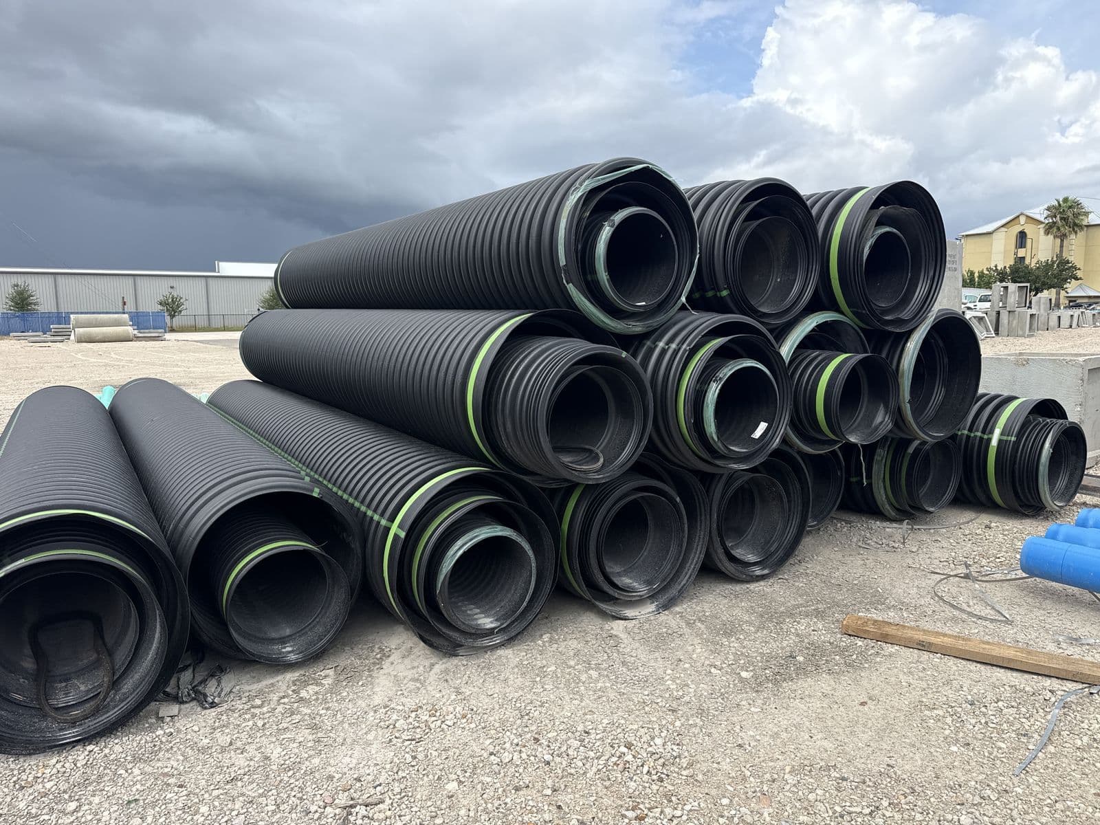Stack of black corrugated HDPE drainage pipe in an outdoor yard