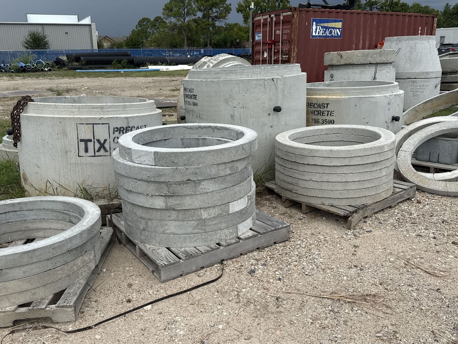 Large round precast concrete manhole sections stacked in an outdoor yard
