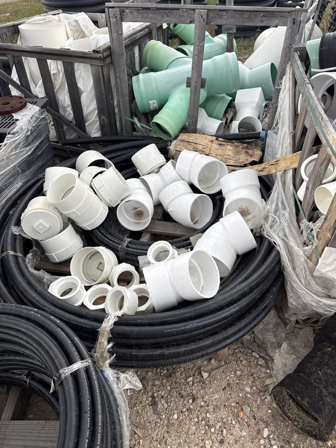 White PVC fittings and a coil of pipe on a pallet