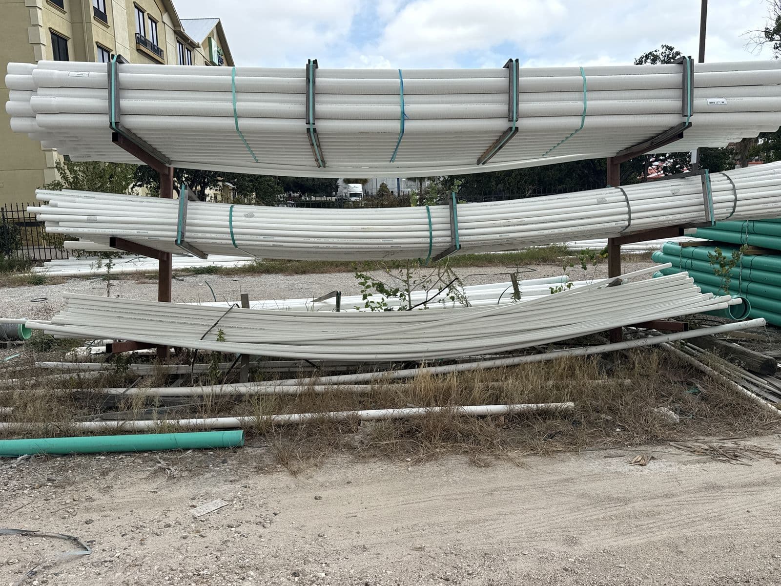 White PVC pipe stored on a metal rack in an outdoor yard